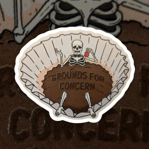 Sticker with skeleton design and 'Grounds for Concern' text on a coffee filter background